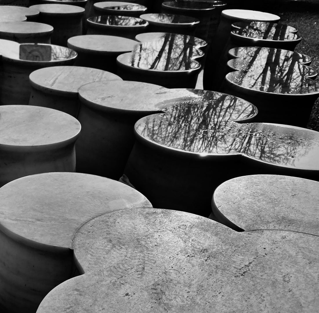 a row of cement pots sitting on top of a grass covered field