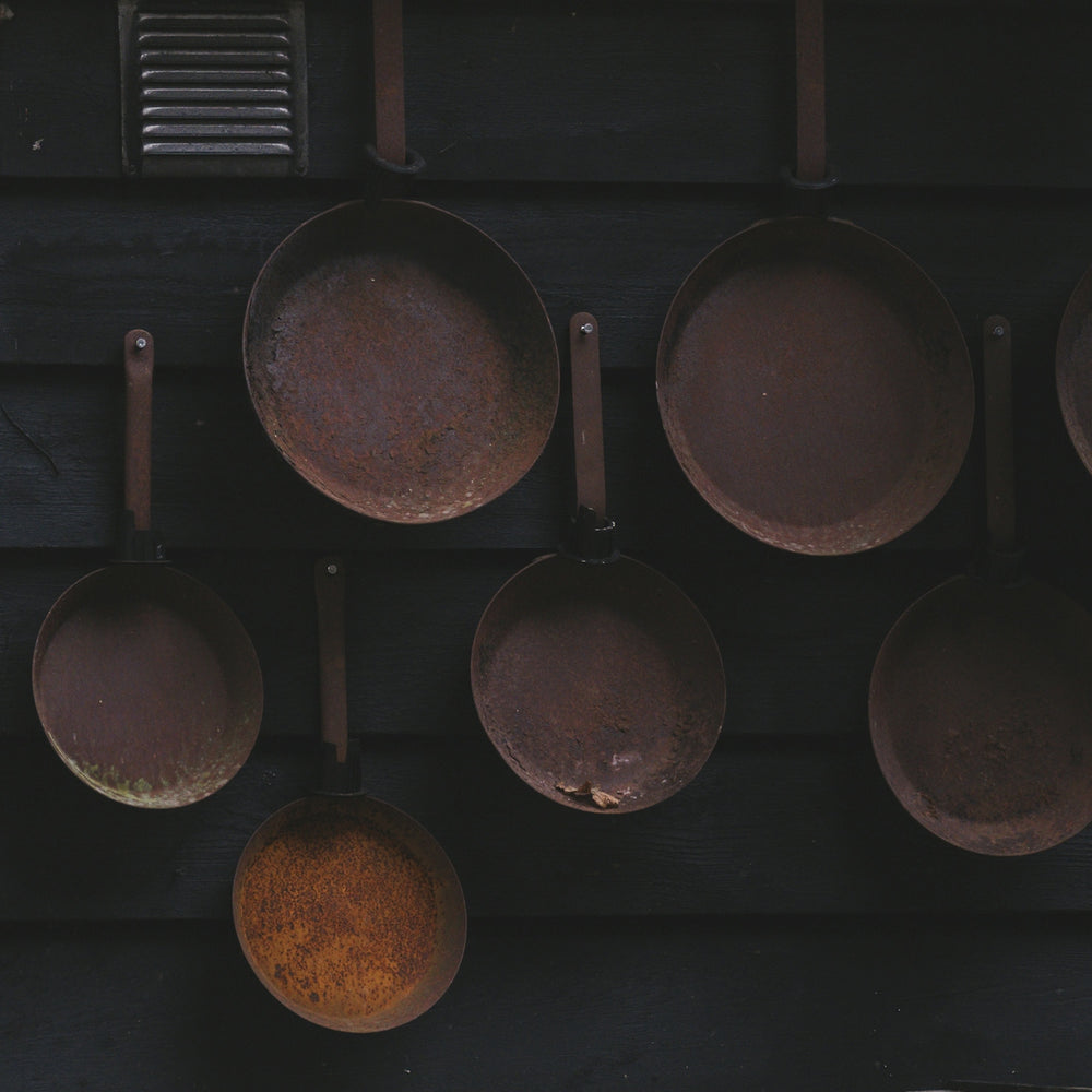 Several old copper pots hanging on a dark wall